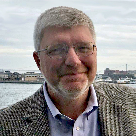 Head shot of Greg Chanis, man with a trimmed beard wearing glasses